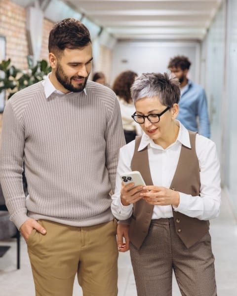 Two colleagues looking at the Vantage Fit app on a phone