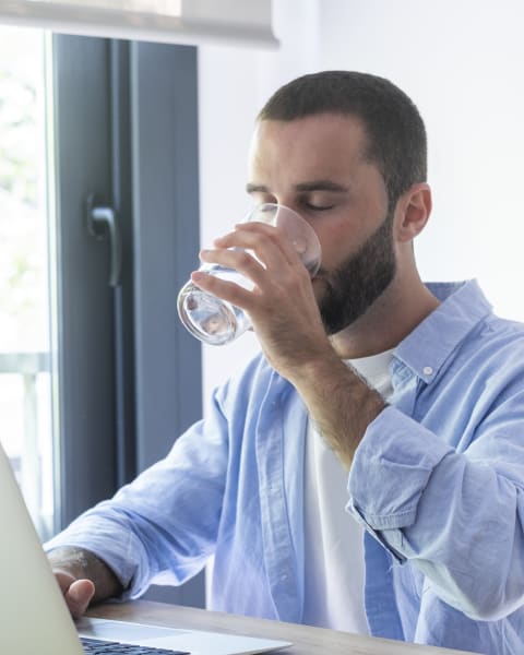 An employee drinking a glass of water at their desk