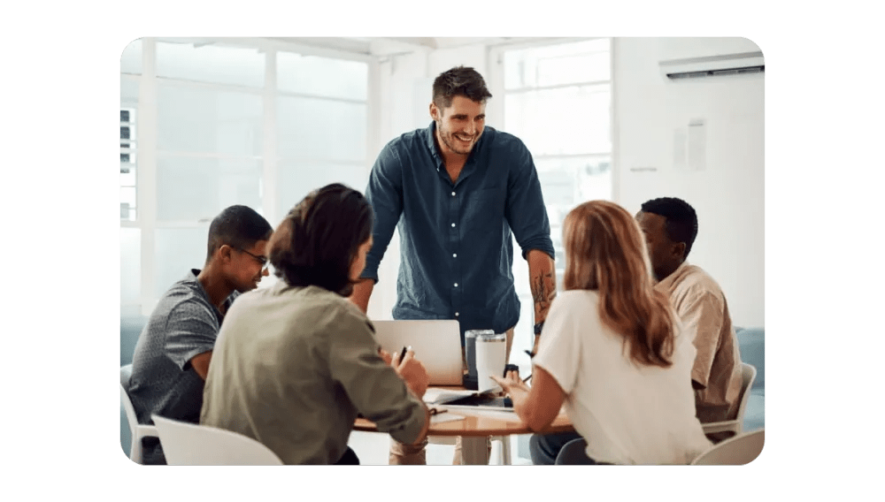 A group of professionals collaborating around a table in a modern office setting, depicting teamwork and effective communication.