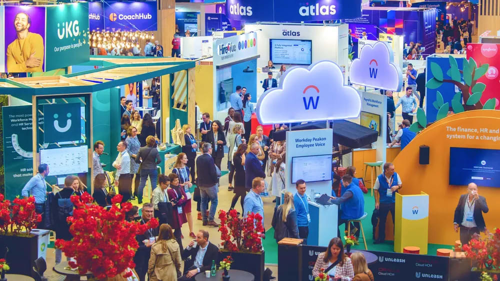 UNLEASH America expo floor packed with HR professionals browsing vendor booths including UKG, CoachHub, and Atlas at the Caesars Forum conference venue