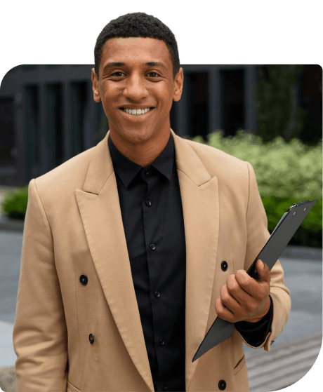 A smiling employee holding a clipboard outside an office building