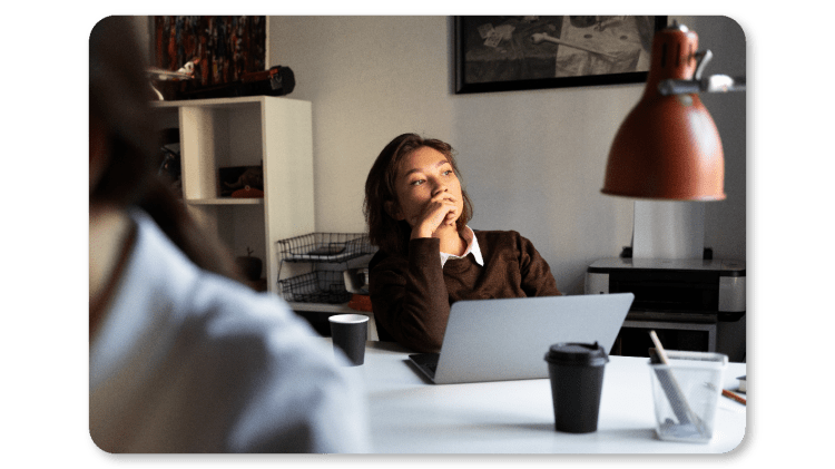 Persona sentada en su puesto de trabajo con gesto de agotamiento, sin capacidad de concentrarse en la tarea.