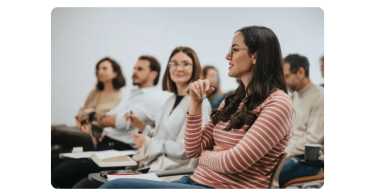Grupo de empleados sentados escuchando durante una sesión en la oficina
