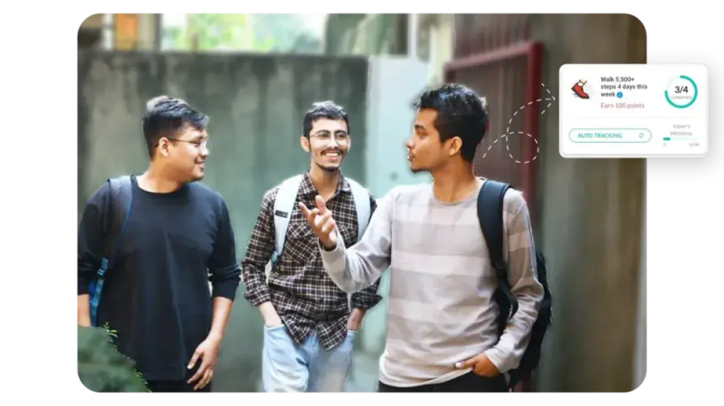 Three young men walking and chatting outdoors with a Vantage Fit step challenge progress widget overlay